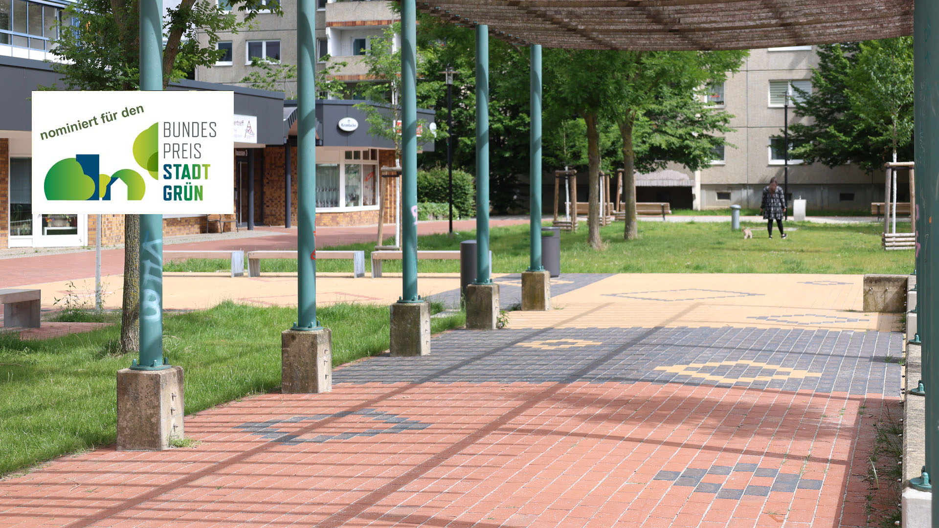 Auf dem Quartiersplatz im Zentrum des Kosmosviertels wurde der Klinkerbelag in einem teppichartigen Muster verlegt. Die vorhandene schattenspendende Pergola bleibt erhalten und wird in einem weitern Bauabschnitt saniert